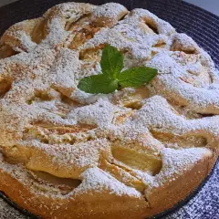 Wilgotne ciasto z jabłkami na oleju, posypane cukrem pudrem i ozdobione listkiem mięty. Idealne na deser.