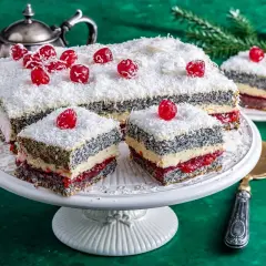 Pyszna makowa panienka z wiśniami i wiórkami kokosowymi, podana na paterze, obok srebrnego czajniczka.