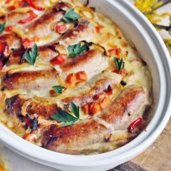 Pyszna biała kiełbasa w sosie chrzanowo-musztardowym, zapieczona z warzywami i udekorowana natką pietruszki. Idealna na wielkanocny stół.