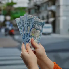 Ręce trzymają węgierskie forinty. Zastanawiasz się, ile kosztuje chleb na Węgrzech?
