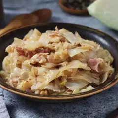 Miseczka pełna tradycyjnych łazanek z kapustą białą i kawałkami boczku. Danie wygląda apetycznie i domowo.