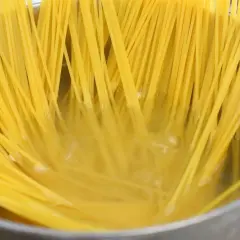 Złocisty makaron spaghetti gotuje się w garnku, osiągając idealny stopień makaron al dente.