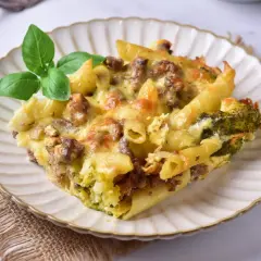 Pyszna zapiekanka makaronowa z mięsem mielonym w sosie śmietanowym, z brokułami i serem, udekorowana bazylią.