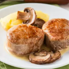Dwa soczyste polędwiczki z grilla podane z puree ziemniaczanym i pieczarkami.