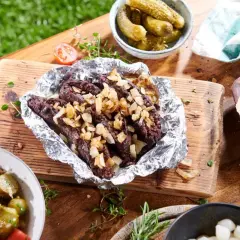 Kaszanka z grilla z cebulą w folii aluminiowej, podana z chlebem, ogórkami i sałatką. Idealna na letnie spotkanie.