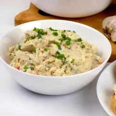 Pyszna pasta z kurczaka, posypana szczypiorkiem, gotowa do podania na świeżym pieczywie. Obok czosnek i cebula.