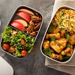 Pyszne air fryer przepisy: kurczak w sosie, ryż z warzywami, sałatka, jabłka i orzechy w pojemnikach na lunch.
