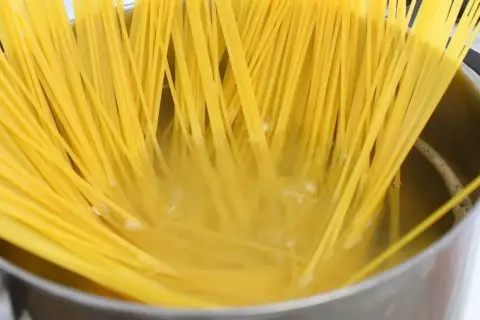 Złocisty makaron spaghetti gotuje się w garnku, osiągając idealny stopień makaron al dente.