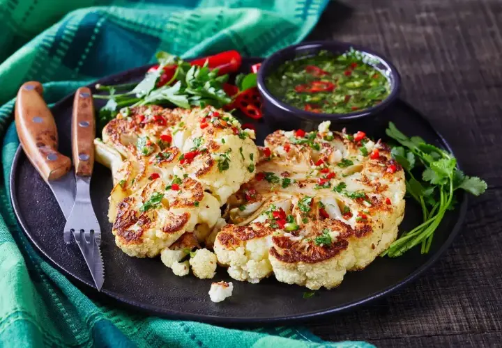 Szybkie danie z kalafiora: pieczone steki z kalafiora z sosem chimichurri, posypane chili i pietruszką.