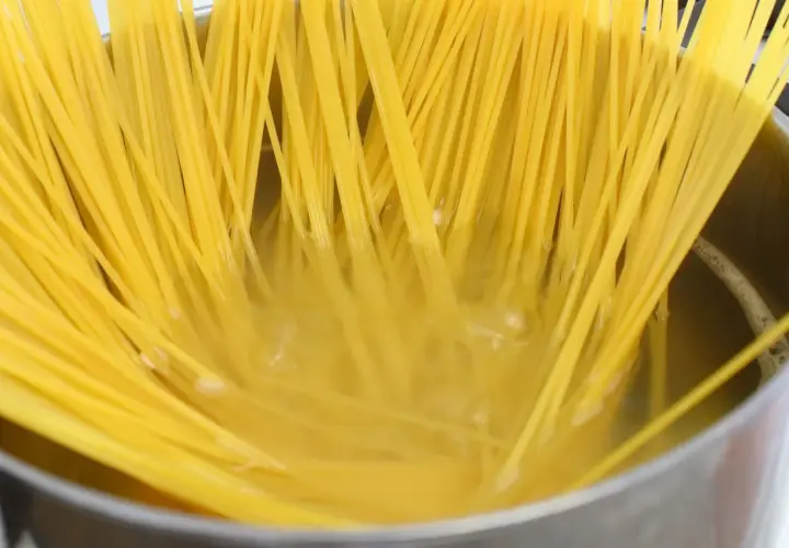 Złocisty makaron spaghetti gotuje się w garnku, osiągając idealny stopień makaron al dente.