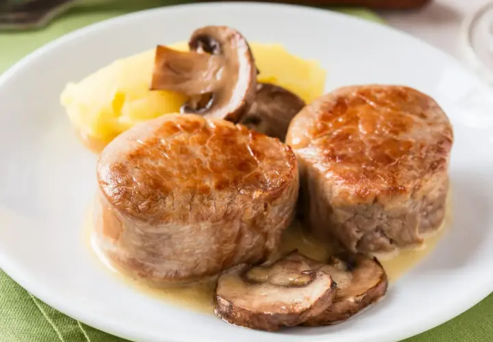 Dwa soczyste polędwiczki z grilla podane z puree ziemniaczanym i pieczarkami.