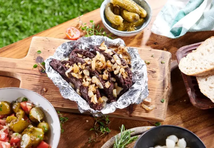 Kaszanka z grilla z cebulą w folii aluminiowej, podana z chlebem, ogórkami i sałatką. Idealna na letnie spotkanie.