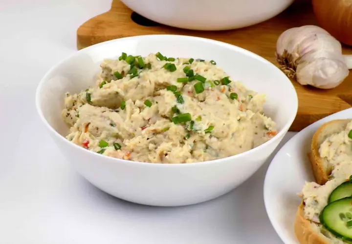 Pyszna pasta z kurczaka, posypana szczypiorkiem, gotowa do podania na świeżym pieczywie. Obok czosnek i cebula.