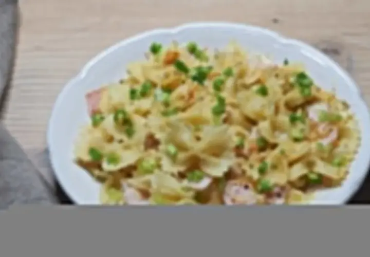 Szybki obiad z makaronem farfalle, szynką i szczypiorkiem, polany kremowym sosem.