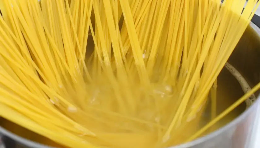 Złocisty makaron spaghetti gotuje się w garnku, osiągając idealny stopień makaron al dente.