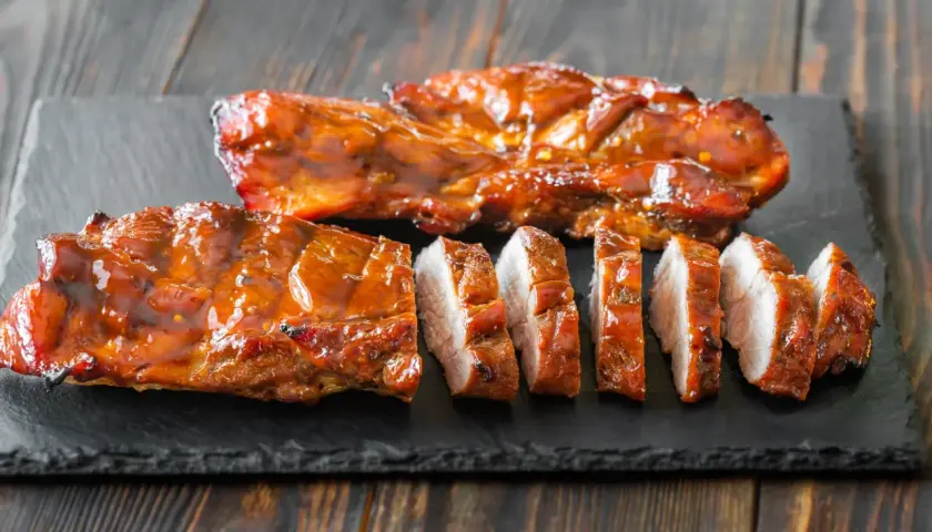 Soczyste, glazurowane żeberka wieprzowe, pokrojone na kawałki. Idealne do grillowania, zastanawiasz się, jak długo wędzić polędwiczki wieprzowe, by osiągnąć taki efekt?