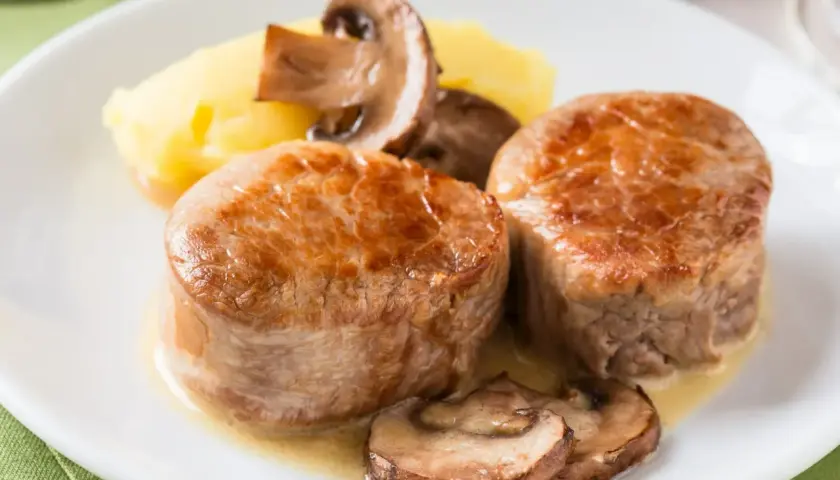 Dwa soczyste polędwiczki z grilla podane z puree ziemniaczanym i pieczarkami.