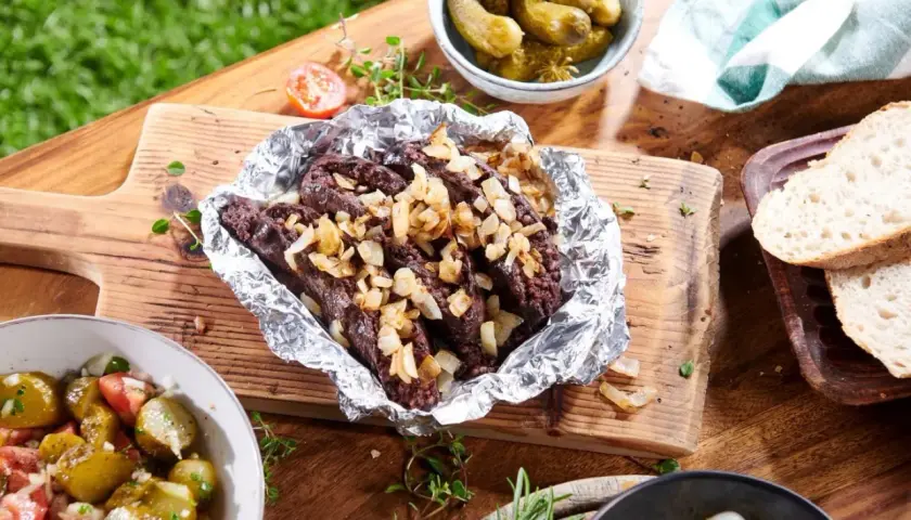 Kaszanka z grilla z cebulą w folii aluminiowej, podana z chlebem, ogórkami i sałatką. Idealna na letnie spotkanie.