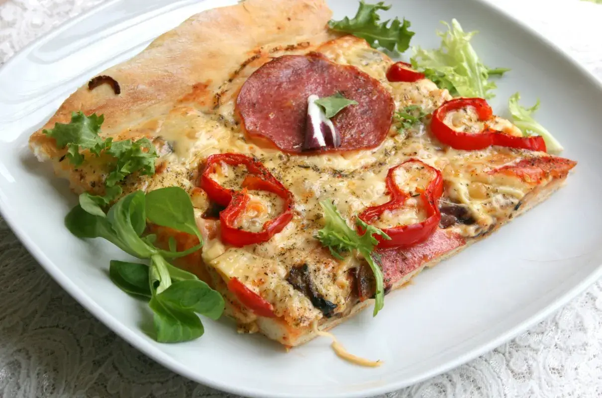Proste ciasto na pizzę zawsze wychodzi, oto kawałek z salami, papryką i serem, udekorowany świeżą sałatką.