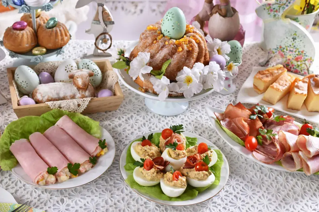 Wielkanocny stół pełen smakołyków: babka, jajka faszerowane, wędliny, ciasto. Idealne inspiracje, co ugotować na święta.