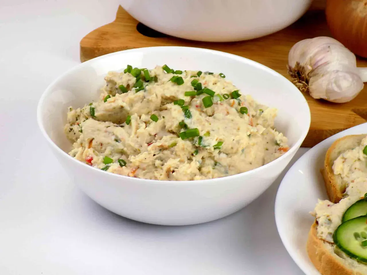 Pyszna pasta z kurczaka, posypana szczypiorkiem, gotowa do podania na świeżym pieczywie. Obok czosnek i cebula.