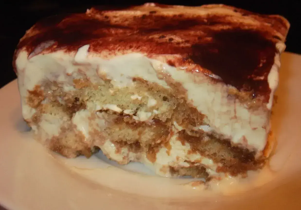 Pyszny kawałek tiramisu bez alkoholu, z warstwami biszkoptów i kremu, posypany kakao.