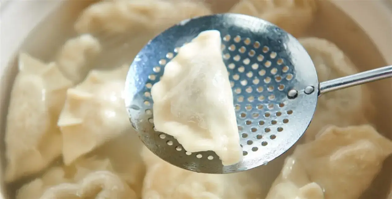 Ugotowane pierogi na łyżce cedzakowej. Aby ugotowane pierogi się nie skleiły, warto dodać łyżkę oleju do wody.