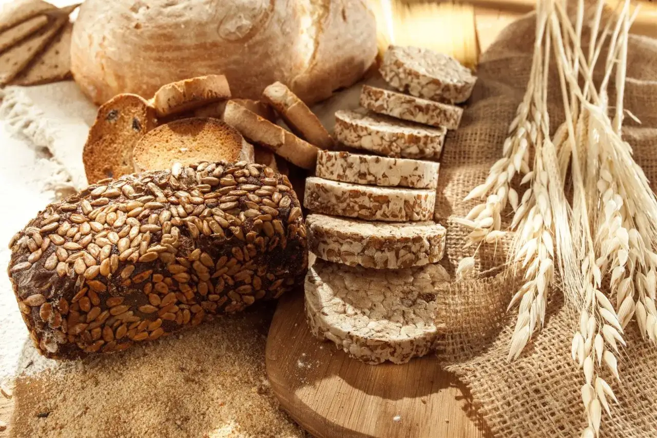 Chleb żytni z ziarnami słonecznika, kromki chleba, wafle ryżowe i kłosy zbóż. Czy chleb żytni ma gluten? Tak, zawiera go.