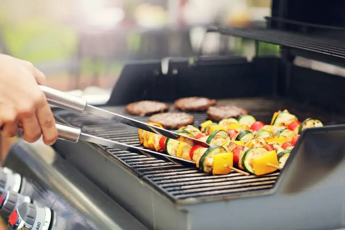 Na grillu piecze się kilka szaszłyków z warzywami i mięsem.