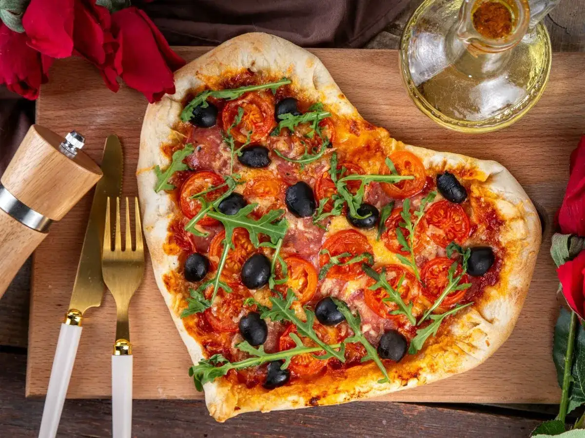 Pizza w kształcie serca z pomidorami, oliwkami i rukolą. Idealna inspiracja, co ugotować na kolację.
