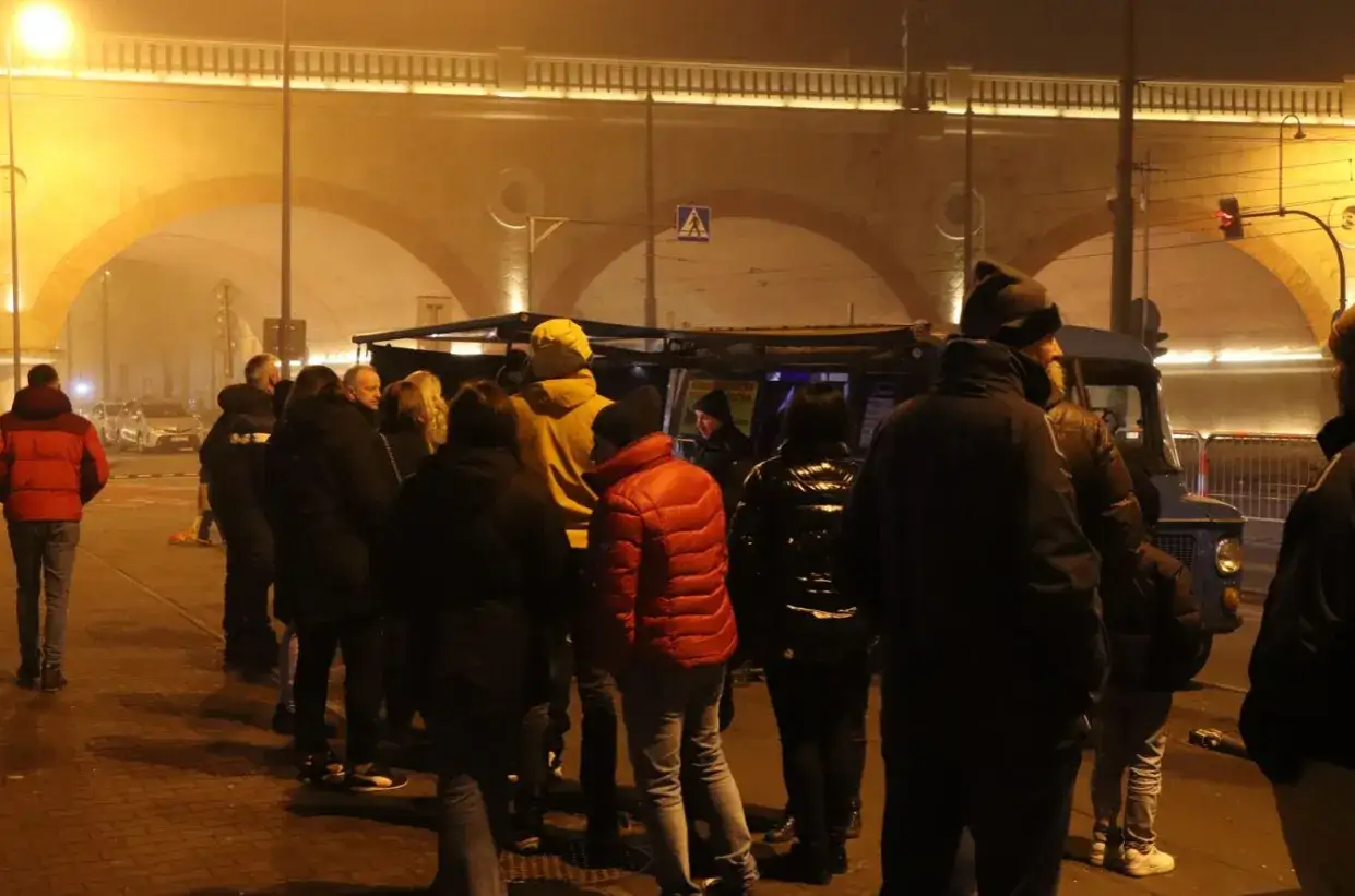 Kolejka po kiełbasę z niebieskiej Nyski pod mostem. Ludzie czekają na ciepły posiłek w zimowy wieczór.