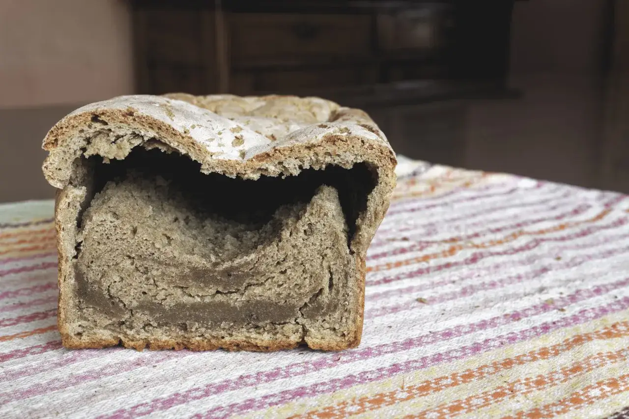 Rozkrojony bochenek chleba z widocznym, wilgotnym wnętrzem. Czy taki mokry chleb w środku można jeść?