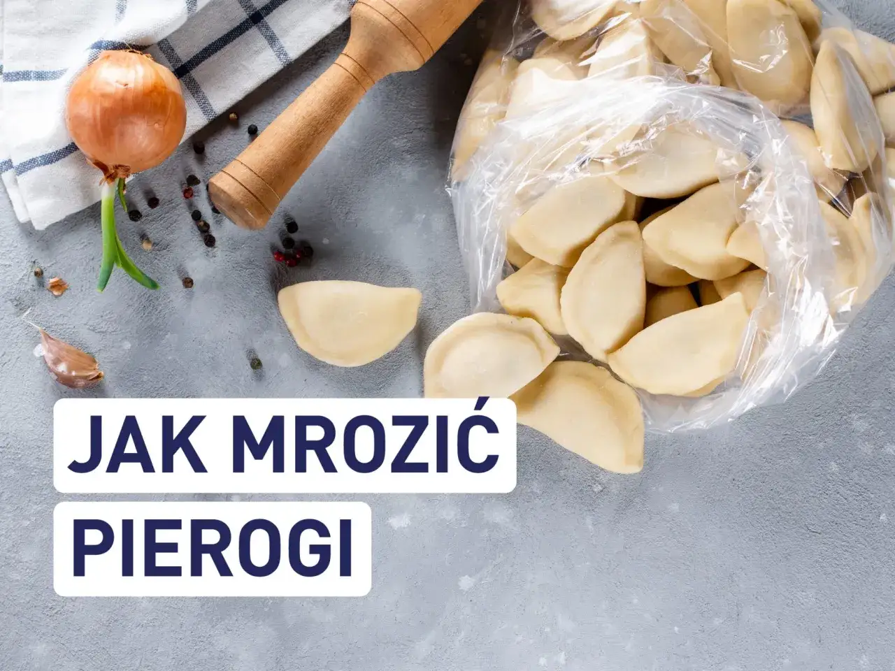 Jak zamrozić pierogi ruskie? Na stole leżą surowe pierogi, cebula, czosnek i wałek.