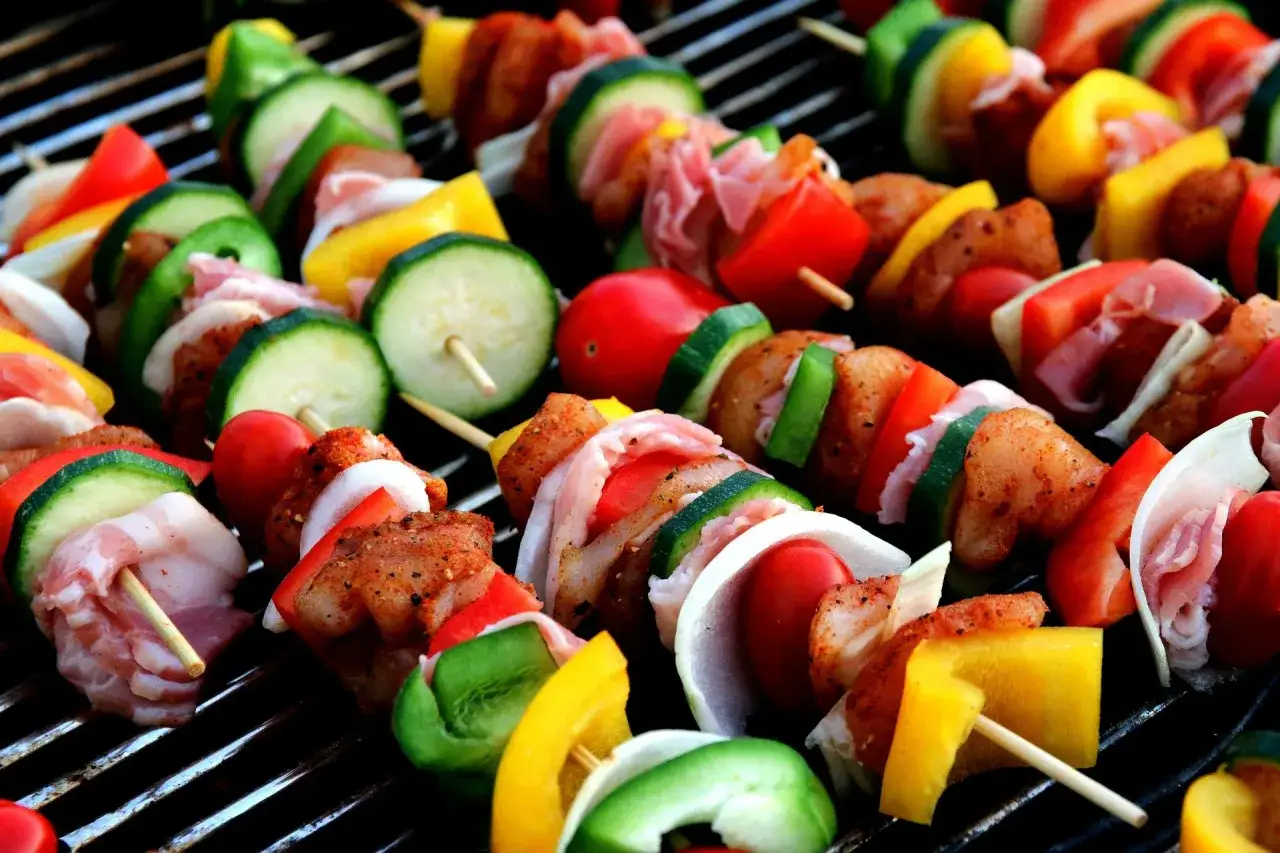 Kolorowe szaszłyki z karkówki, papryki, cukinii i pomidorów pieką się na grillu. Idealne na lato, pokazują jak zrobić szaszłyki z karkówki.