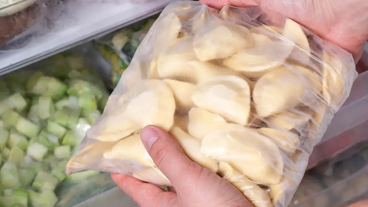 Ręce trzymają worek z pierogami, gotowe do zamrożenia. To świetny sposób, jak pakować pierogi próżniowo, by zachowały świeżość.