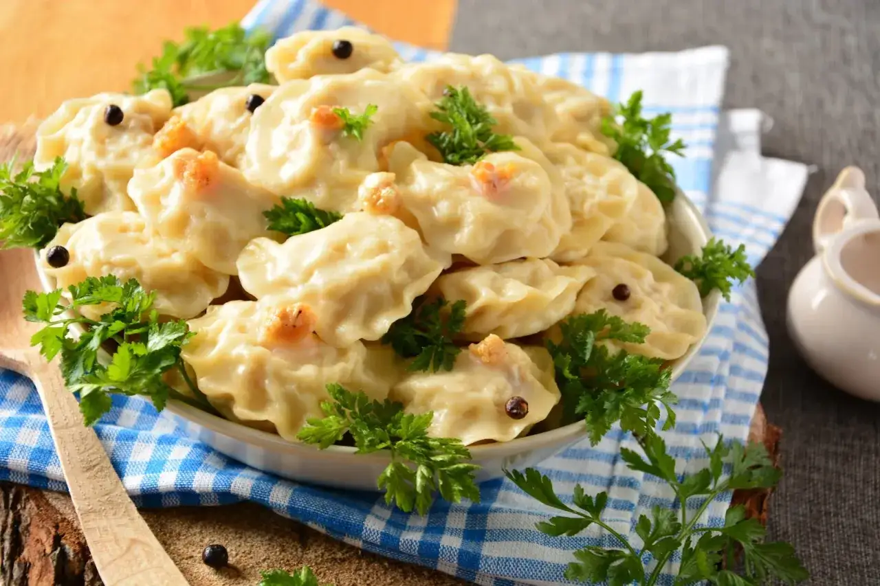 Pyszne, domowe pierogi, które zachęcają, by dowiedzieć się, jak zrobić pierogi. Udekorowane natką pietruszki i pieprzem.