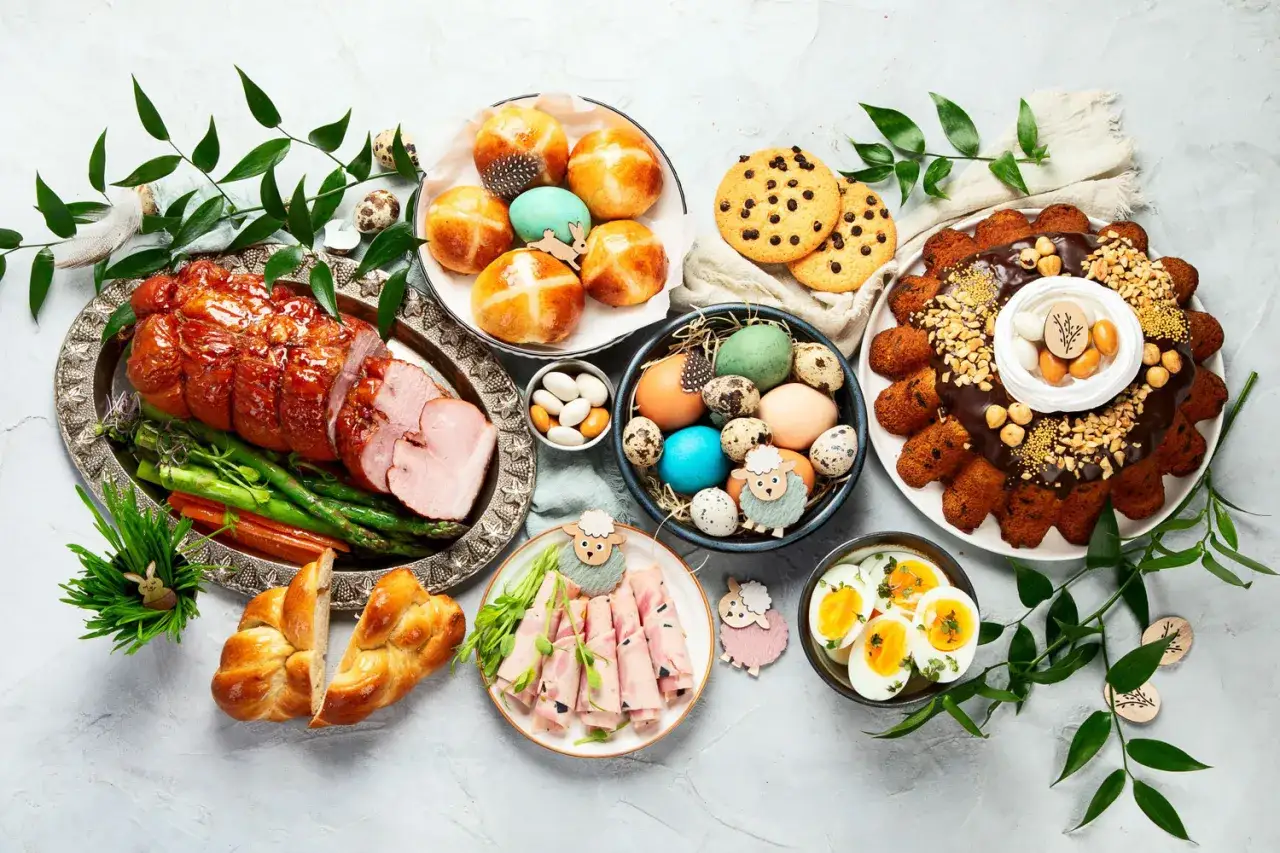 Wielkanocny st&oacute;ł pełen pyszności: pieczona szynka, babki, jajka, ciasto i inne smakołyki. Idealne inspiracje, co ugotować na święta.