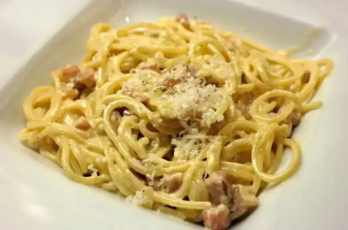 Spaghetti carbonara - przepis oryginalny ze śmietaną. Kremowy sos, kawałki guanciale i parmezan na makaronie.