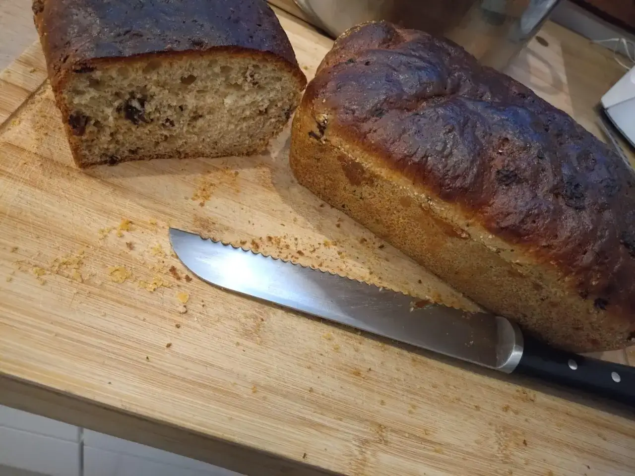 Dwa bochenki chleba na desce, jeden przekrojony. Czy pies może jeść chleb? N&oacute;ż czeka na kromkę.