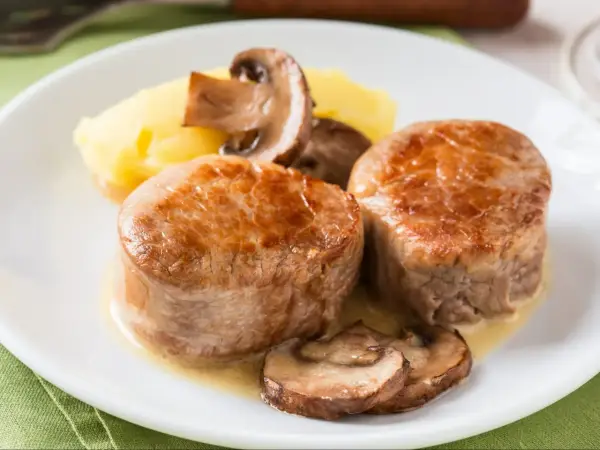 Dwa soczyste polędwiczki z grilla podane z puree ziemniaczanym i pieczarkami.