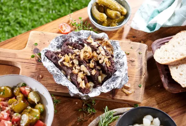 Kaszanka z grilla z cebulą w folii aluminiowej, podana z chlebem, ogórkami i sałatką. Idealna na letnie spotkanie.